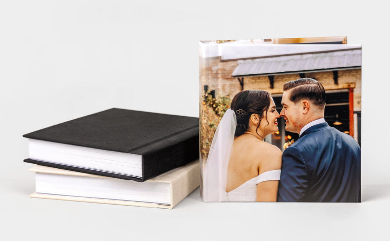 Three Wedding Album99s, two laying next to a third Album99 that features an image of a recently married man and woman.