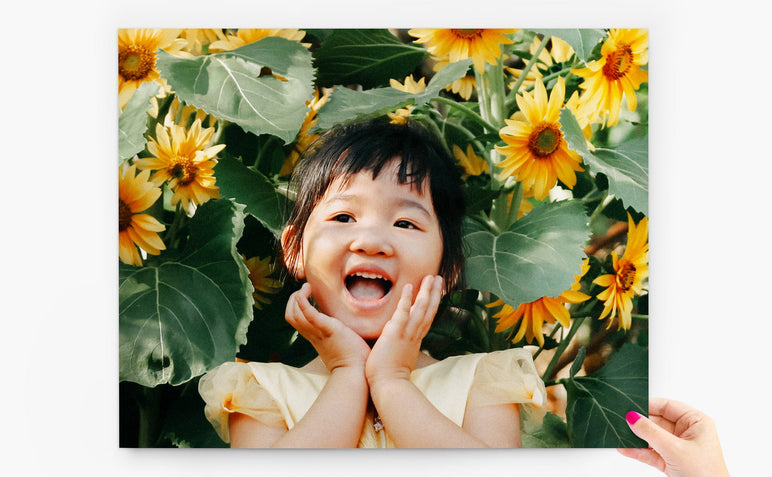 11x14" Photo Print being held by a woman's hand. The Photo Print features a young child with sunflowers around her.