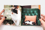 A Buzz Book being held open by a woman, the book pages feature two photos of rad looking cats.