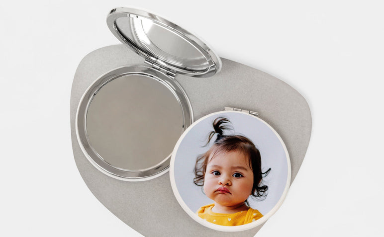 Two Compact Mirrors, one open and the other with a photo of a small child on the cover. 