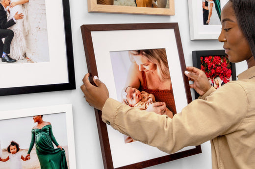 Close up image of a woman hanging an Espresso Framed Print