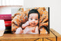5x7" Gallery Block styled on a bedside table featuring a photo of a baby on an orange blanket. 