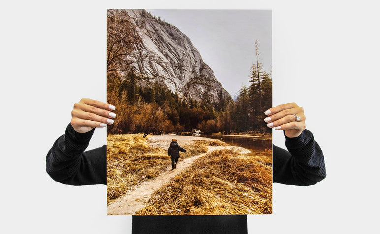 Woman holding up a 16x20" Portrait Lustre Photo Print with a picture of a child on a hiking trail.