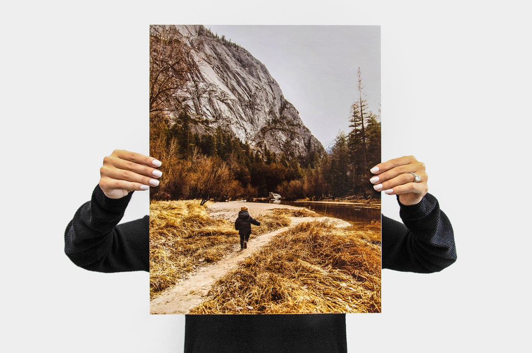 Woman holding up a 16x20" Portrait Lustre Photo Print with a picture of a child on a hiking trail.