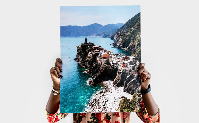Woman holding a 18x24" Photo Print featuring a picture of a coastal town. 