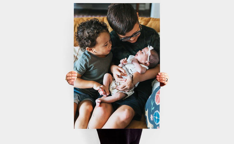 Woman holding a 30x45" Photo Print featuring a picture of two kids holding a baby.