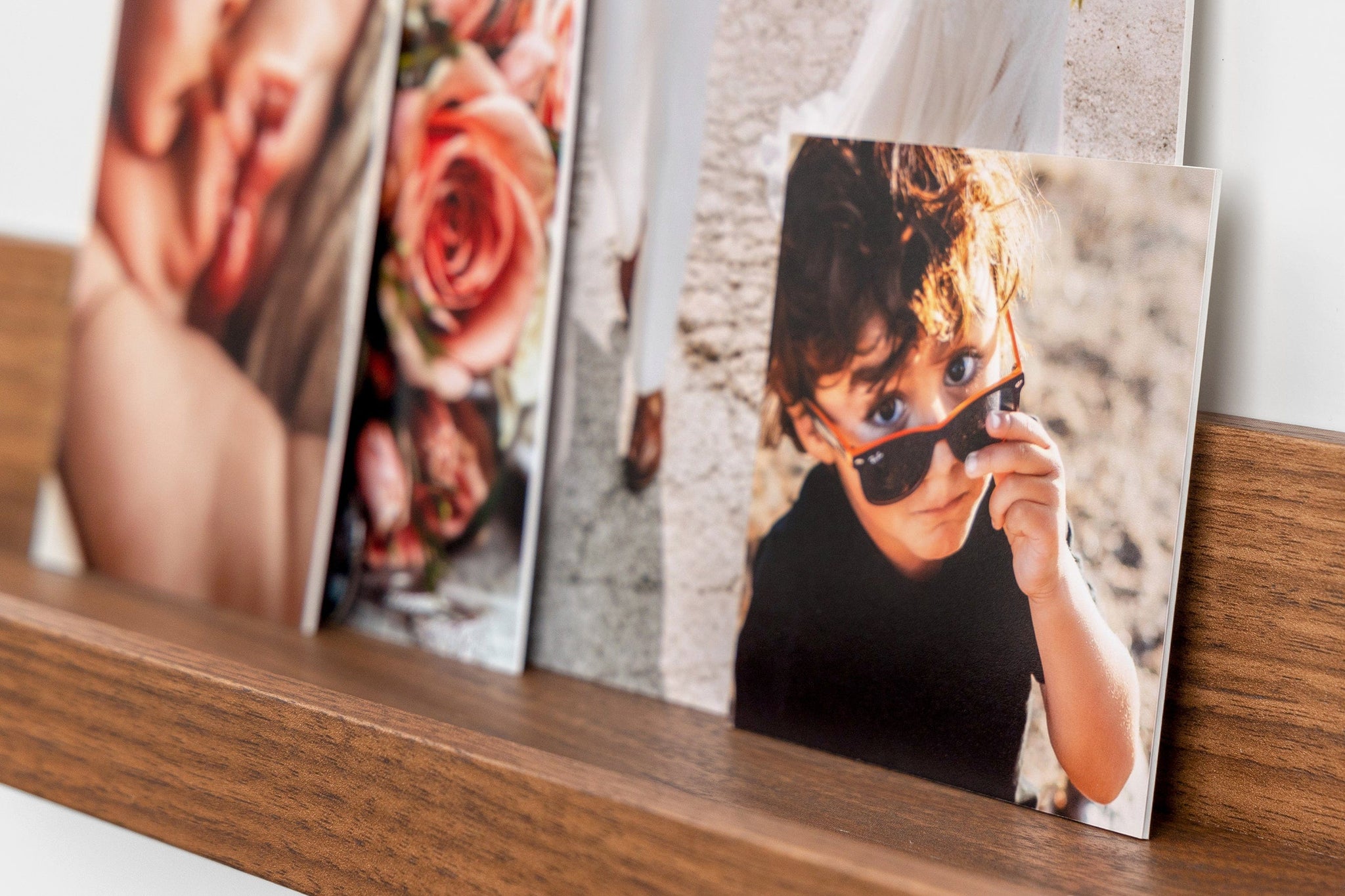 Four photo prints mounted on Single Weight Matboard styled on a photo ledge. The focus image is 4x4" and features a child wearing sunglasses.