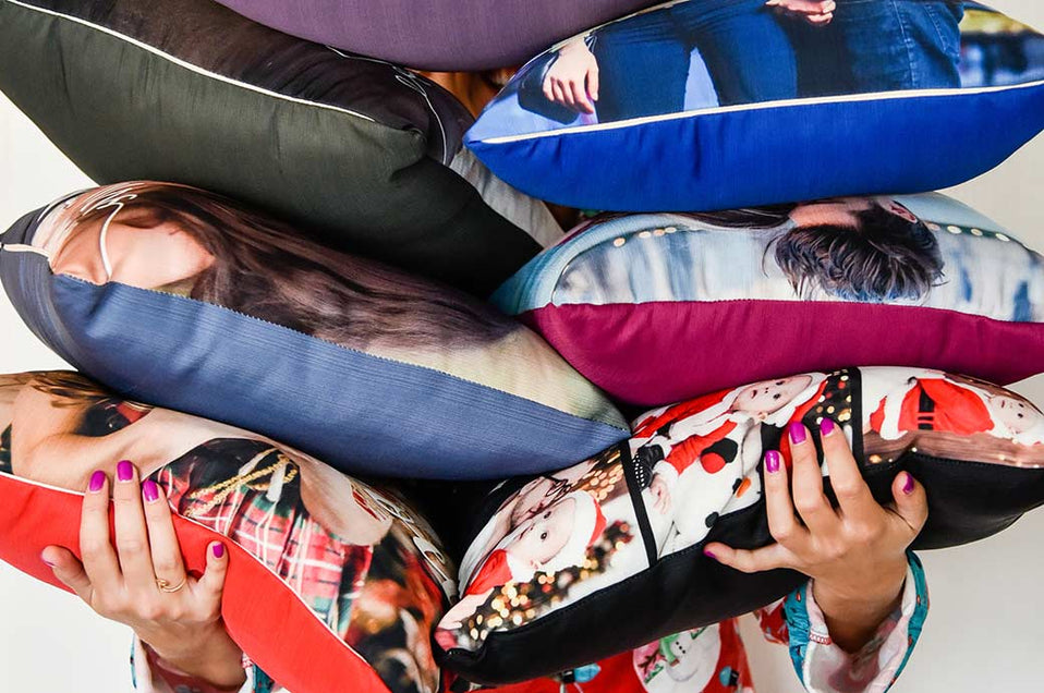 Woman holding several Photo Pillows stacked on top of each other.