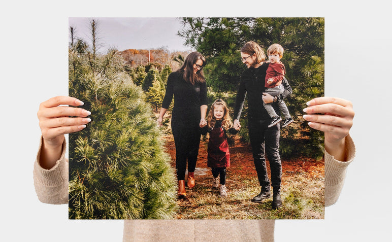 Woman holding up a 16x20" Landscape Lustre Photo Print with a picture of a family in a Christmas tree farm.