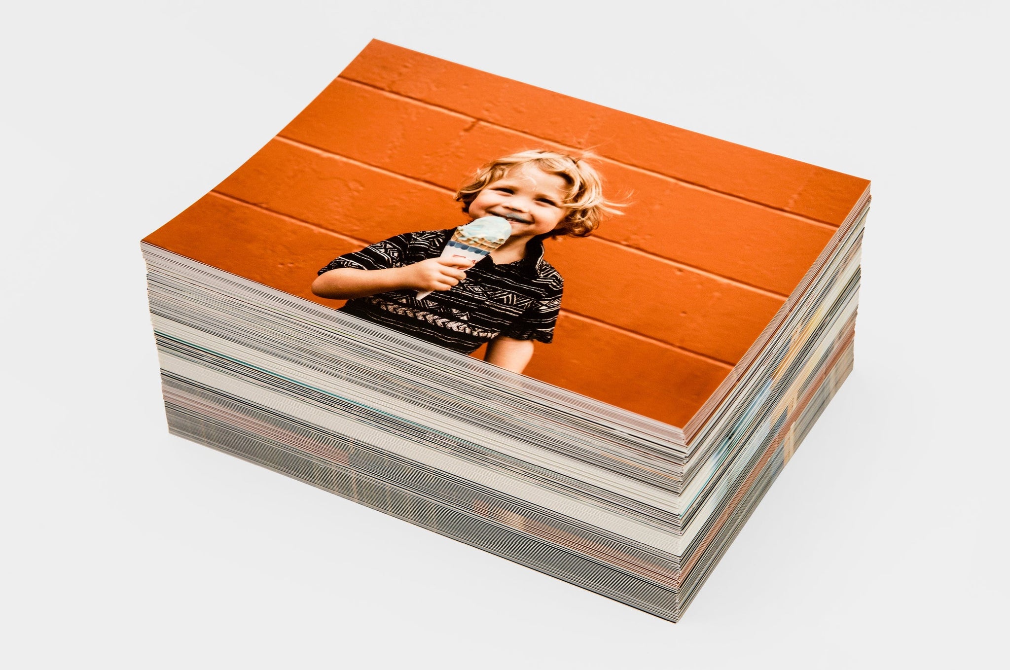 Large stack of 5x7" Volume Photo Prints, the top photo features a picture of a boy with ice cream.