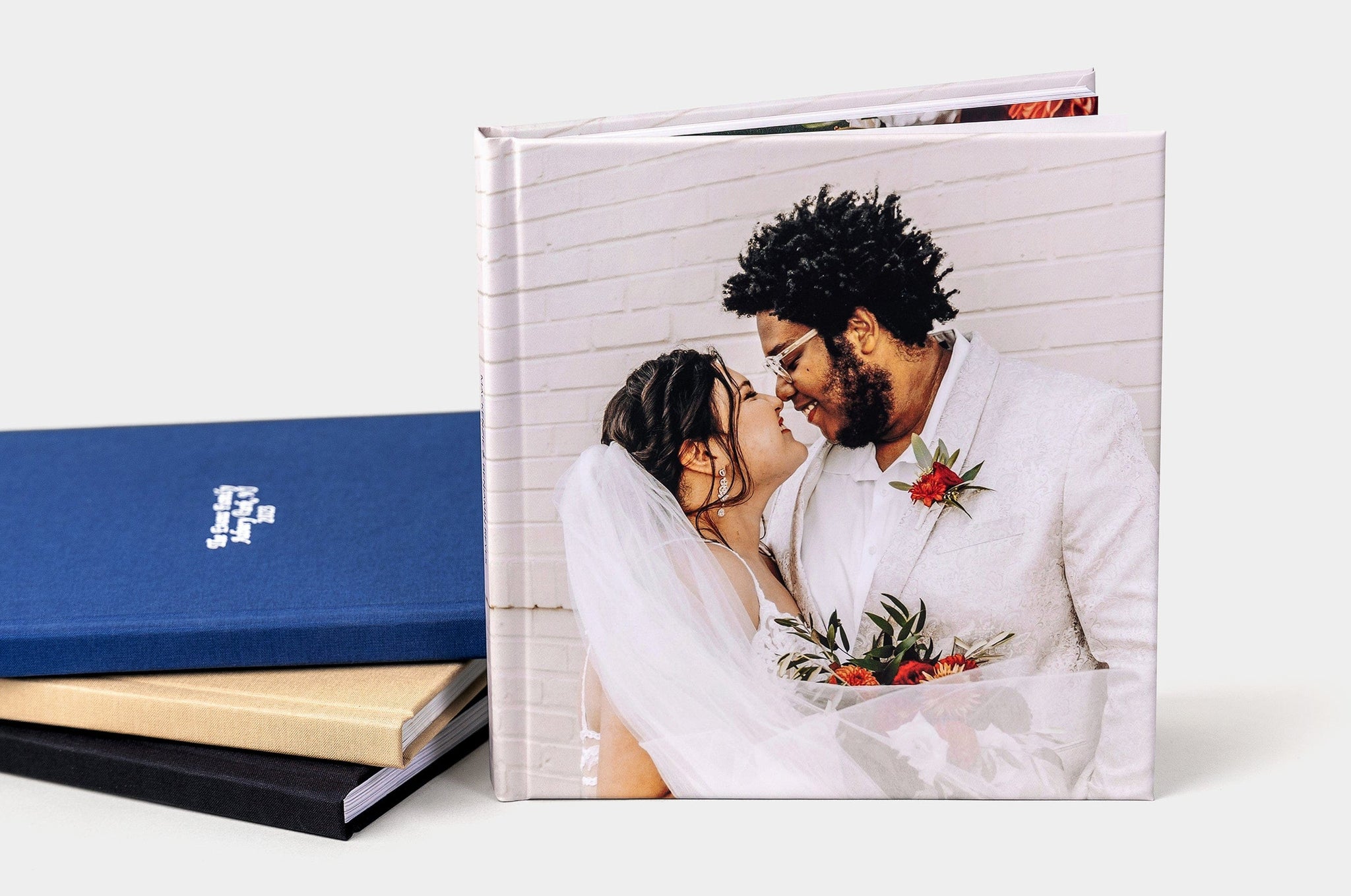 Four Photo Books arranged in a fetching manner, the main focus is a book with a Lustre Photo Cover featuring a happy bride and groom.