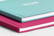 Two Hardcover Photo Books stacked together, featured covers are Seamist Linen and Mulberry Linen